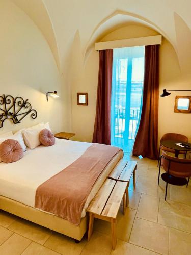 a bedroom with a bed and a table and a window at Palazzo Matà Boutique Hotel in Taranto