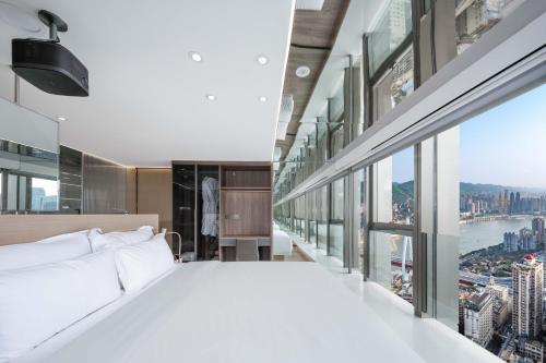 a bedroom with a large white bed and a large window at 重庆Indition英迪逊高空酒店 解放碑来福士店 in Chongqing