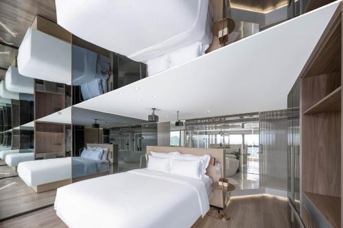 a bedroom with a large white bed and glass walls at 重庆Indition英迪逊高空酒店 解放碑来福士店 in Chongqing