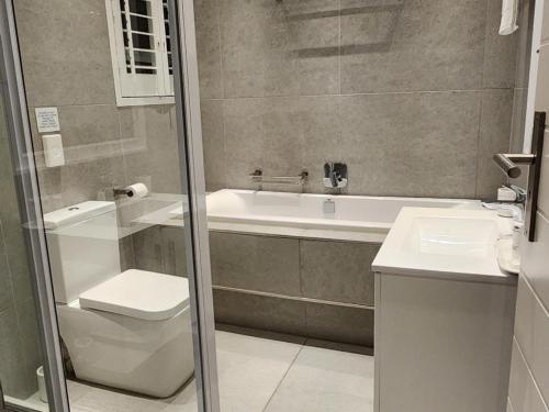 a bathroom with a tub and a toilet and a sink at Frinton on Sea 12 in Ballito