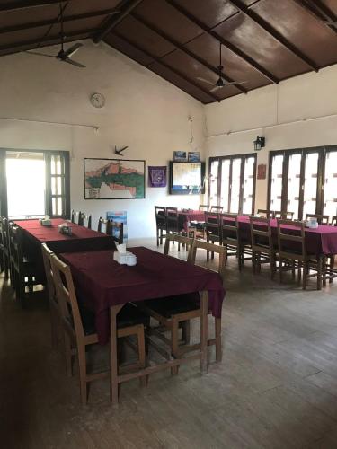 a dining room with tables and chairs and windows at Tiger Residency Resort in Sauraha