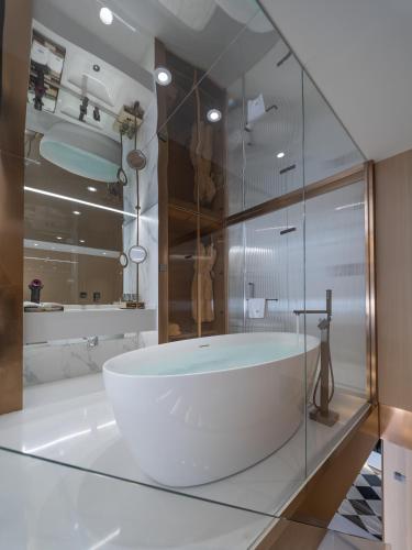 a white tub in a bathroom with a glass wall at 重庆Indition英迪逊高空酒店 解放碑来福士店 in Chongqing
