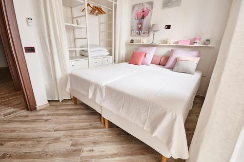 a bedroom with a large white bed with pink pillows at San Vito Charme Apartment in Ischia