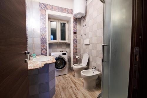 a bathroom with a toilet sink and a washing machine at San Vito Charme Apartment in Ischia