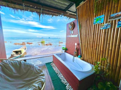 a bath tub in a room with a view of the ocean at Bnเกาะลิบงโฮมสเตย์ in Ko Libong