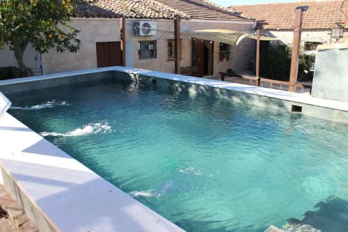 a swimming pool with blue water in front of a house at La Tejuela - Casa en Andújar independiente con piscina in Los Villares