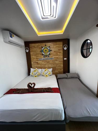 two beds in a room with a clock on the wall at Bnเกาะลิบงโฮมสเตย์ in Ko Libong