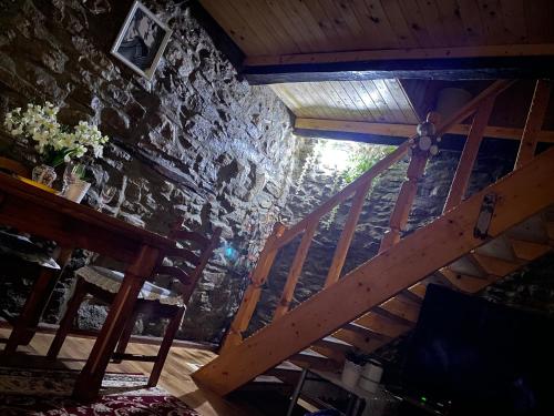an attic room with a wooden staircase and a stone wall at ANTICA BAITA in Gergei