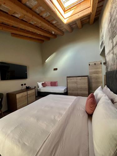 a bedroom with a large white bed and a television at Ida Boutique Hotel in Casa Marcolin