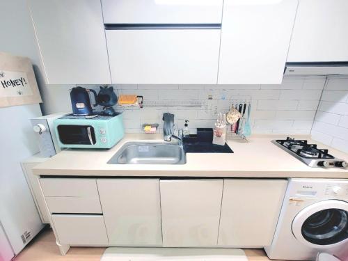 a kitchen with a sink and a microwave at Like U Residence in Goyang