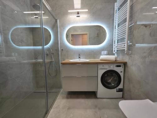 a bathroom with a sink and a washing machine at Apolonia Apartamenty III - SPA in Dziwnów