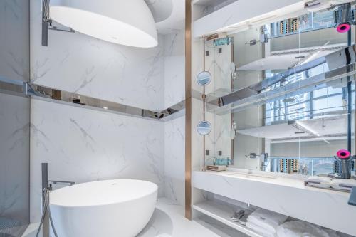 a white bathroom with a sink and a mirror at 重庆Indition英迪逊高空酒店 解放碑来福士店 in Chongqing