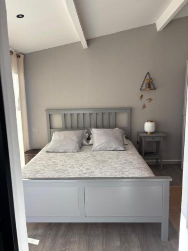 une chambre avec un grand lit blanc dans une pièce dans l'établissement Les Mésanges, à Castelnau-le-Lez