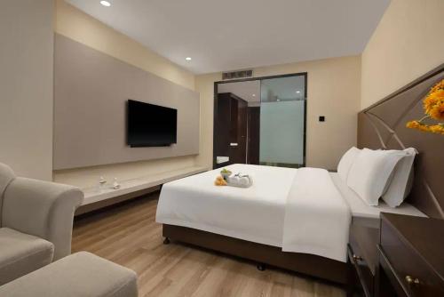 a bedroom with a large white bed and a tv at Manston Hotel Gaoxin Science Avenue Subway Station Branch in Hefei