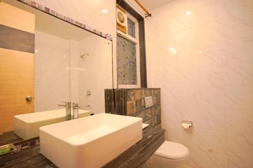 a bathroom with a white sink and a toilet at Chirping Hills Resort,Bhimtal in Bhīm Tāl