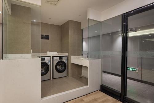 a laundry room with a washer and dryer at Manston Hotel Gaoxin Science Avenue Subway Station Branch in Hefei
