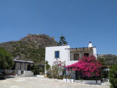 a white building with pink flowers in front of a mountain at Kouvaras Apartments in Kýthira