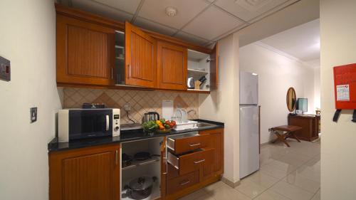 a kitchen with wooden cabinets and a microwave at Rose Garden Hotel Apartments - Bur Dubai in Dubai