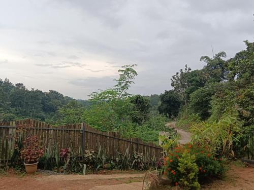 a wooden fence next to a dirt road at Royal Valley Apartment in Kalpetta
