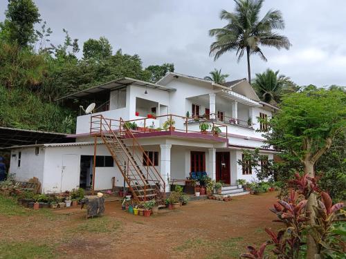 a white house with a staircase in front of it at Royal Valley Apartment in Kalpetta