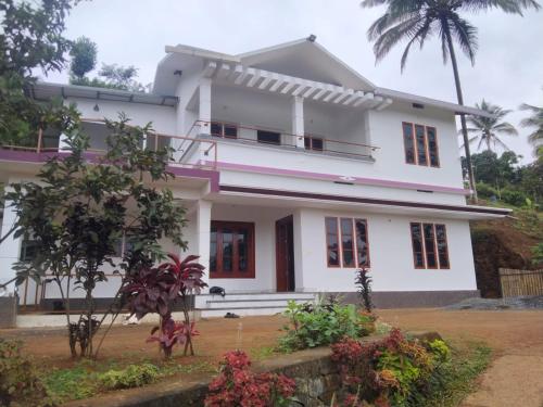 a white house with palm trees in the background at Royal Valley Apartment in Kalpetta