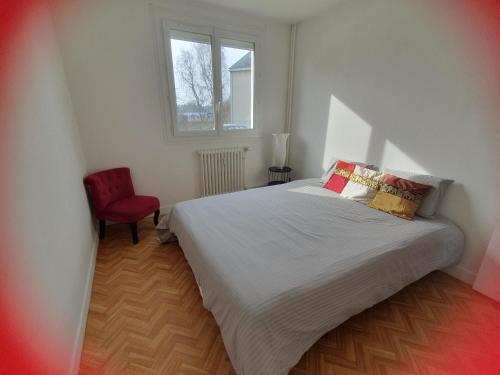 une chambre avec un lit et une chaise rouge dans l'établissement Le nouveau monde, à Bayeux