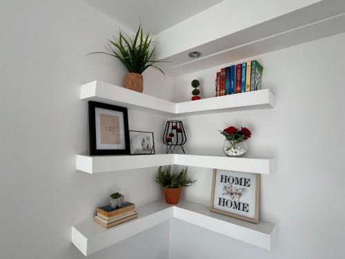 a wall with white shelves with books and plants at Villa Evita - Sea View Apartment by Kostas in Afitos
