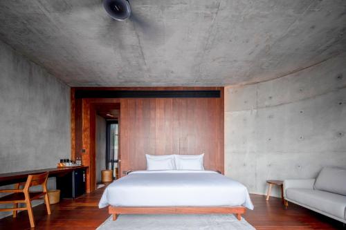 a bedroom with a white bed and a couch at Vows Villa Beachfront in Ban Bang Po