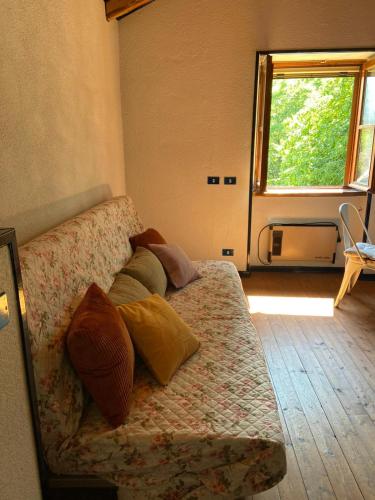 a couch with pillows on it in a room with a window at La Casetta Della Mamy in Mergozzo