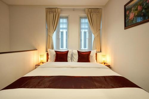 a bedroom with a large bed with two windows at Nivas Wanit 3BR 1SFB Yaowarat MRT EntireHome 85SQM in Bangkok