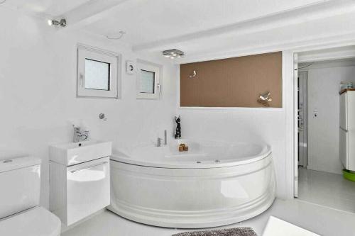 a white bathroom with a tub and a sink at Lovely House By The Water With Cozy Courtyard in Thyholm