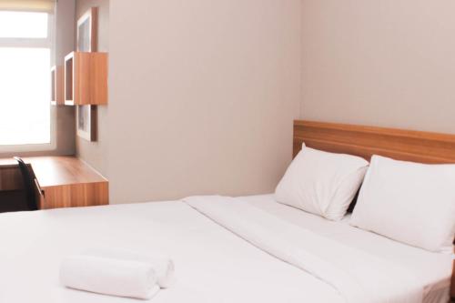 a bedroom with a bed with white sheets and a window at Fancy and Comfy 2BR Apartment at Springlake Summarecon By Travelio in Bekasi