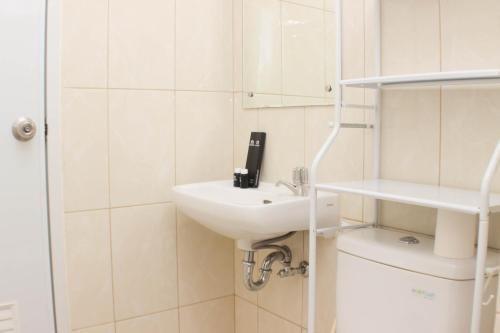 a white bathroom with a sink and a toilet at Fancy and Comfy 2BR Apartment at Springlake Summarecon By Travelio in Bekasi