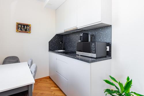 a kitchen with white cabinets and a microwave at Bangų g. Apartamentai in Klaipėda