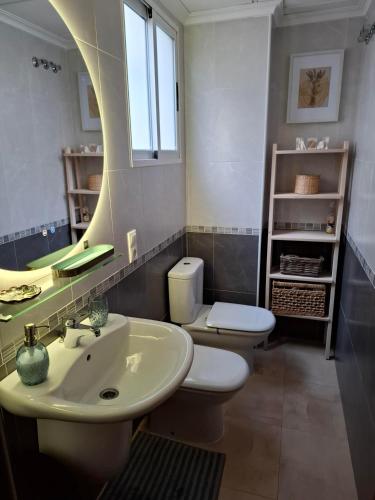 a bathroom with a sink and a toilet and a mirror at Ático Pola in Santa Pola