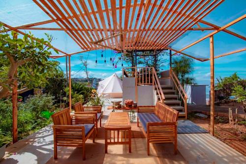 a patio with chairs and tables under a wooden pergola at Santolina Homestay - Tây Hồ Hill in Da Lat