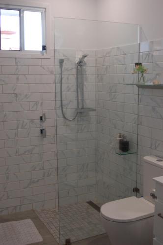 a bathroom with a glass shower with a toilet at Affordable full house for family and pet friendly in Taperoo