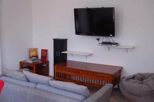 a living room with two couches and a flat screen tv at Affordable full house for family and pet friendly in Taperoo