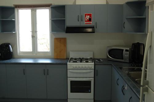 a kitchen with a stove and a microwave at Affordable full house for family and pet friendly in Taperoo