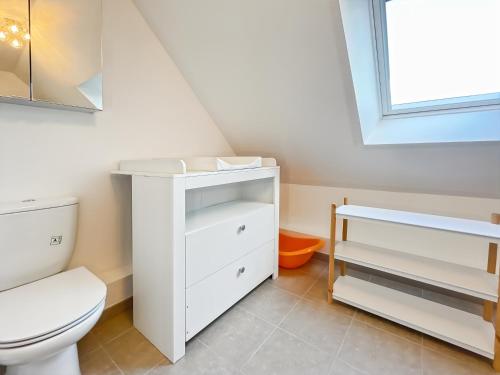a white bathroom with a toilet and a window at Villa Ti Ar Mor - Jardin & Plages à 300m in Hirel