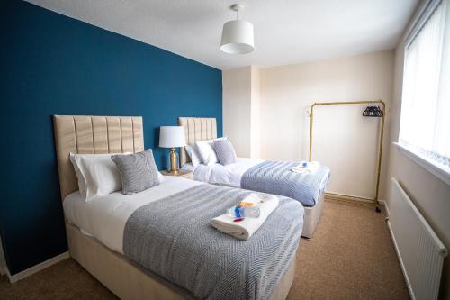 a bedroom with two beds and a blue wall at Richard Gardens in Bathgate
