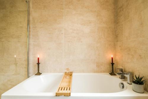 a bathroom with a bath tub with two candles at Entire 4-Bedroom Home Surrey in Sunbury Common