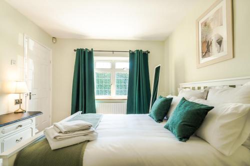 a white bed with green pillows and a window at Entire 4-Bedroom Home Surrey in Sunbury Common