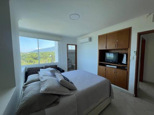 ein Schlafzimmer mit einem Bett mit Kissen und einem Fenster in der Unterkunft Unwind in Santa Martas Oceanfront Retreat in Playa Dormida