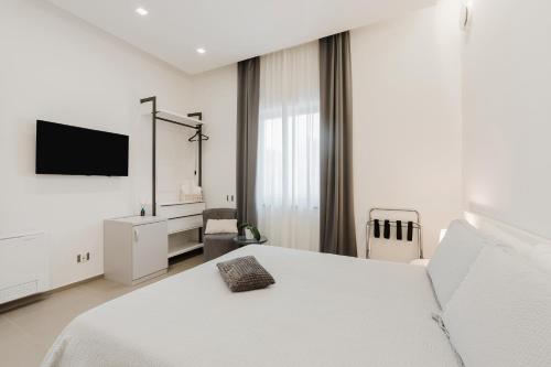 a white bedroom with a bed and a tv at Casa Umeli with Jacuzzi and Sauna in Marsala