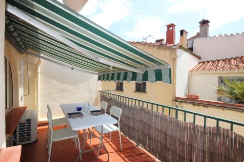 un patio avec une table et des chaises blanches sur un balcon dans l'établissement Le Poisson Bleu, à Collioure