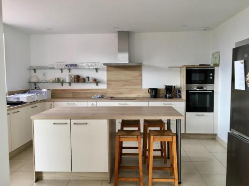 une cuisine avec des armoires blanches et une table en bois dans l'établissement La Vigie, à Crozon