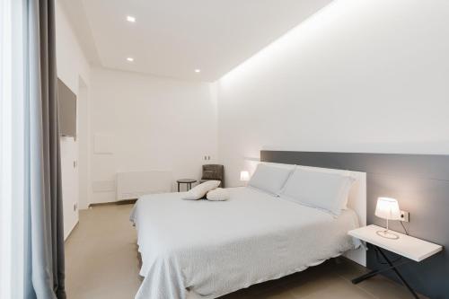 a white bedroom with a white bed and two lamps at Casa Umeli with Jacuzzi and Sauna in Marsala