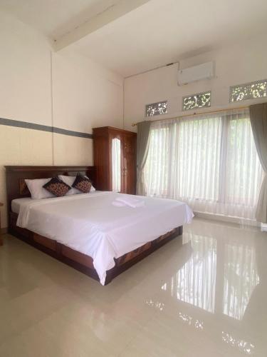 a bedroom with a bed with white sheets and windows at Sri Sedana Guest House in Sidemen