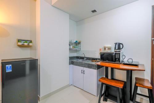 a small kitchen with a counter and a microwave at Best View 2BR at Transpark Cibubur Apartment with Sofa Bed By Travelio in Depok